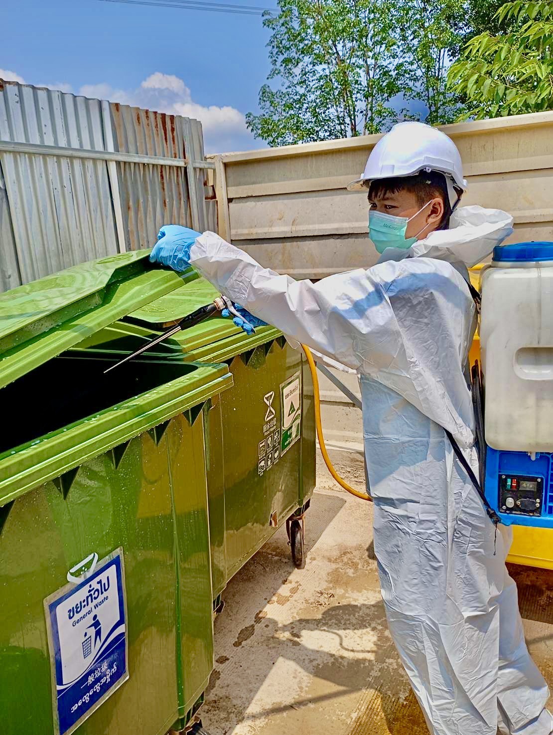 เจ้าหน้าที่สวมชุด PPE ฉีดพ่นเคมีควบคุมแมลงภายในถังขยะคลังสินค้า เพื่อตัดวงจรกำจัดแมลงสาบและยุงตามหลัก IPM ของ WHO
